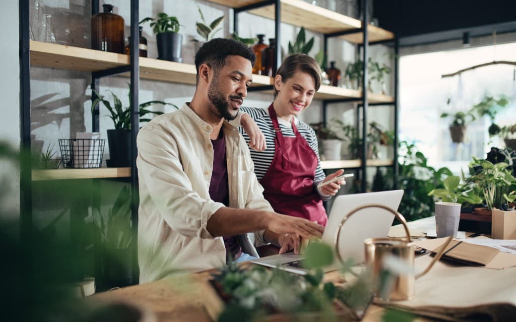 Illustrative photo of two people working on a laptop at a shop counter
