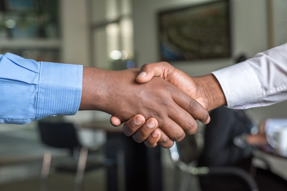 Two professionals shaking hands over a desk in an office